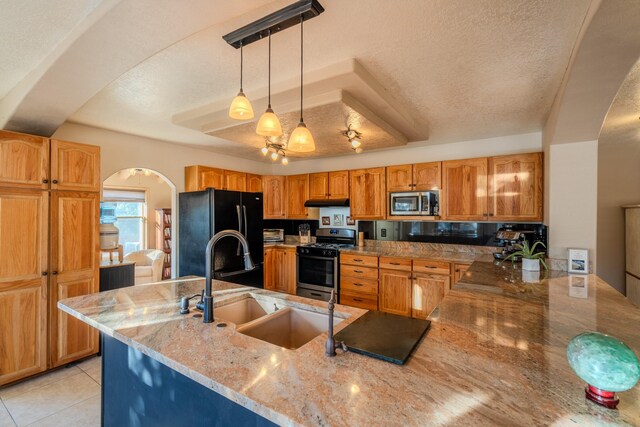 kitchen with light tile patterned floors, light stone countertops, a textured ceiling, and appliances with stainless steel finishes