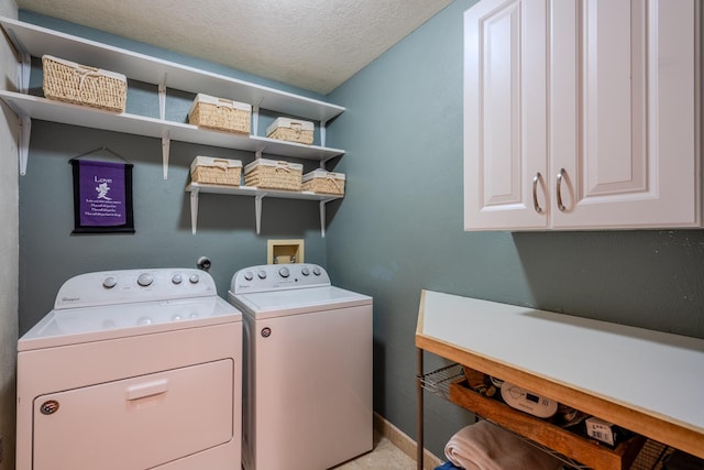 laundry room with a textured ceiling, baseboards, cabinet space, and washer and dryer