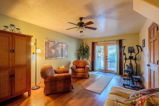 living area featuring a textured ceiling, a ceiling fan, hardwood / wood-style floors, and french doors