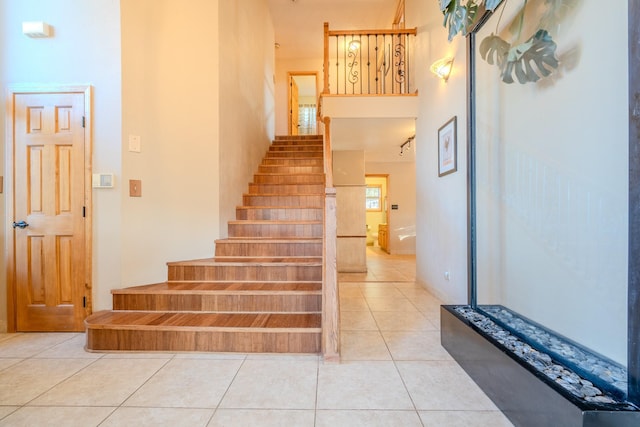 stairway with a high ceiling and tile patterned floors