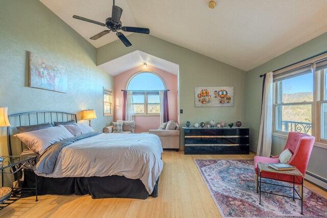 bedroom featuring lofted ceiling, a baseboard heating unit, light hardwood / wood-style flooring, and ceiling fan