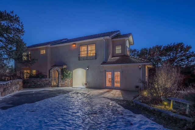 back of house with stucco siding, a tile roof, and french doors