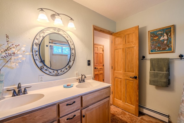 full bath with a textured wall, double vanity, baseboard heating, and a sink