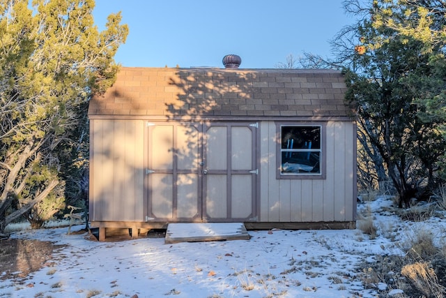 snow covered structure with a storage shed and an outdoor structure