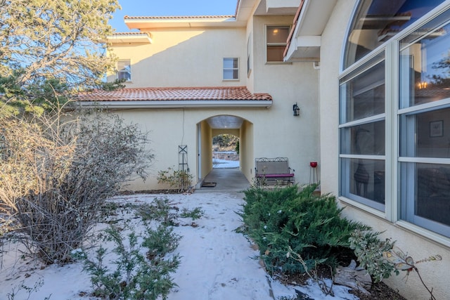 view of exterior entry featuring a tiled roof and stucco siding