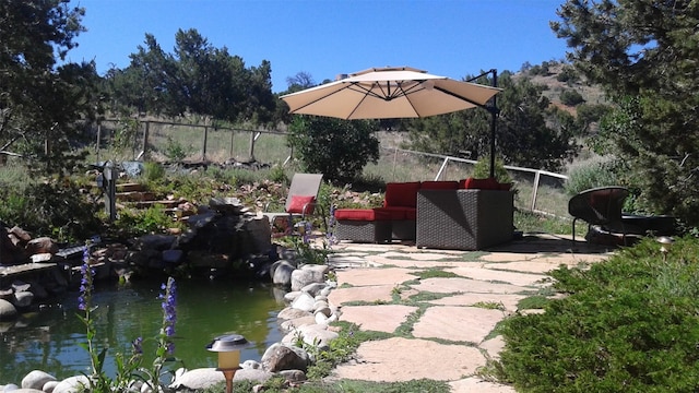 view of patio / terrace featuring a garden pond and fence