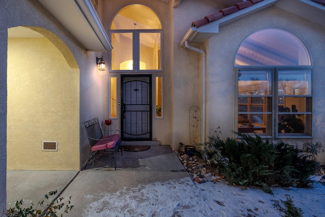 entrance to property with visible vents and stucco siding