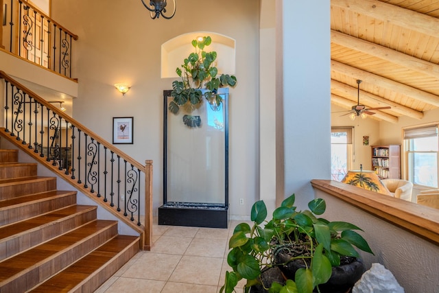 foyer entrance featuring high vaulted ceiling, wooden ceiling, light tile patterned floors, ceiling fan, and beam ceiling