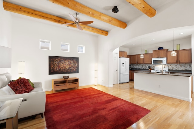 living room featuring ceiling fan, light hardwood / wood-style flooring, and beamed ceiling