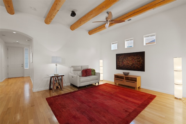 unfurnished living room with ceiling fan, a healthy amount of sunlight, light hardwood / wood-style floors, and beam ceiling