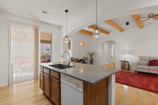 kitchen featuring a kitchen island with sink, white dishwasher, pendant lighting, light stone counters, and sink