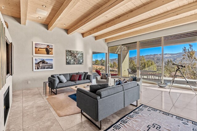 living room with a mountain view, beam ceiling, light tile patterned floors, and wooden ceiling