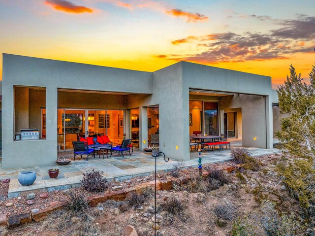 back house at dusk featuring an outdoor living space with a fire pit and a patio