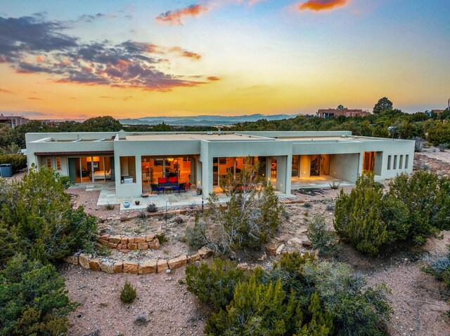 back house at dusk with a patio area