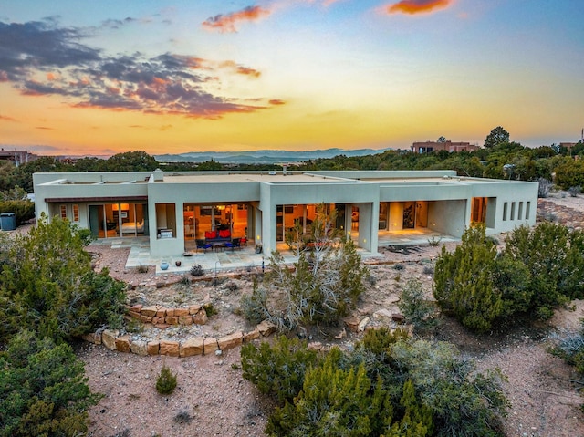 back house at dusk featuring a patio