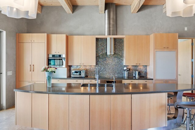 kitchen featuring wood ceiling, a center island with sink, beamed ceiling, light brown cabinetry, and oven