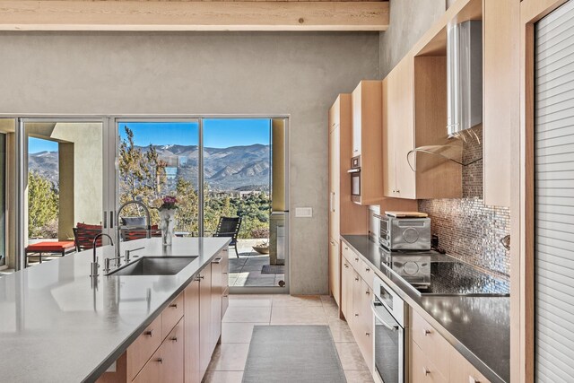 kitchen featuring sink, light tile patterned flooring, a mountain view, and oven