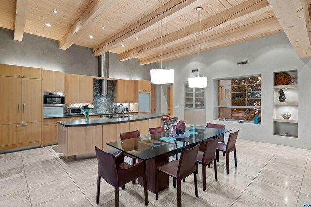 dining space with wooden ceiling, a towering ceiling, built in shelves, beam ceiling, and sink