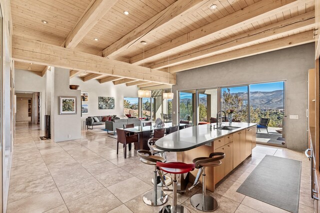 kitchen featuring sink, beamed ceiling, a mountain view, a center island with sink, and wood ceiling