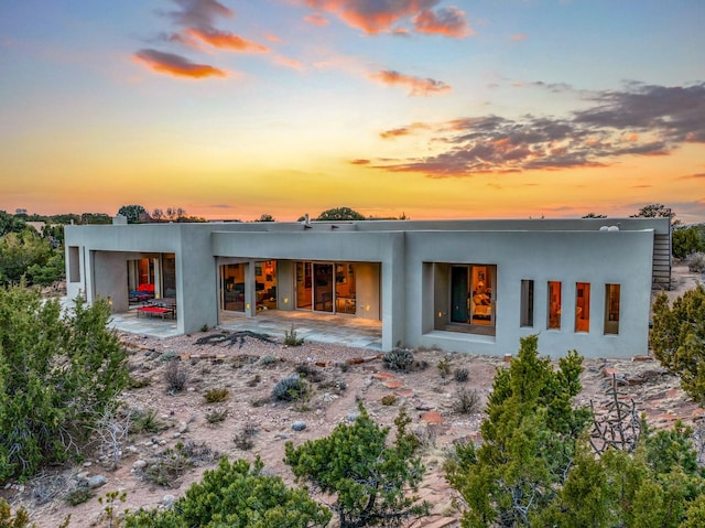 back house at dusk with a patio area