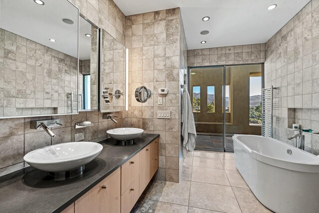 bathroom with tile walls, a bathtub, tile patterned flooring, and vanity