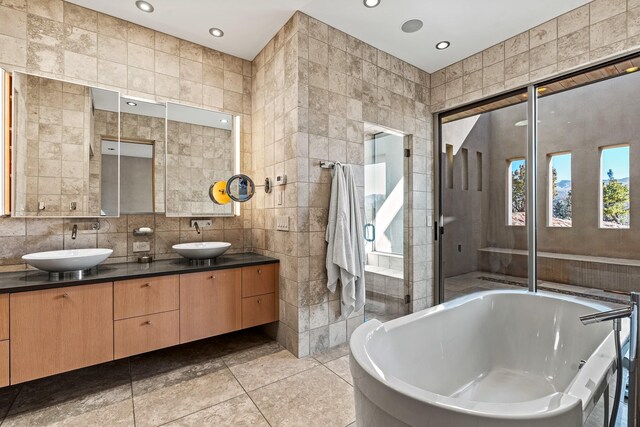 bathroom featuring tile patterned flooring, vanity, tile walls, and plus walk in shower