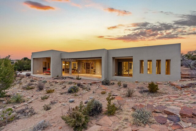 back house at dusk featuring a patio area