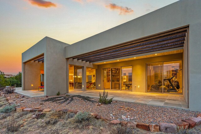 back house at dusk with a patio area