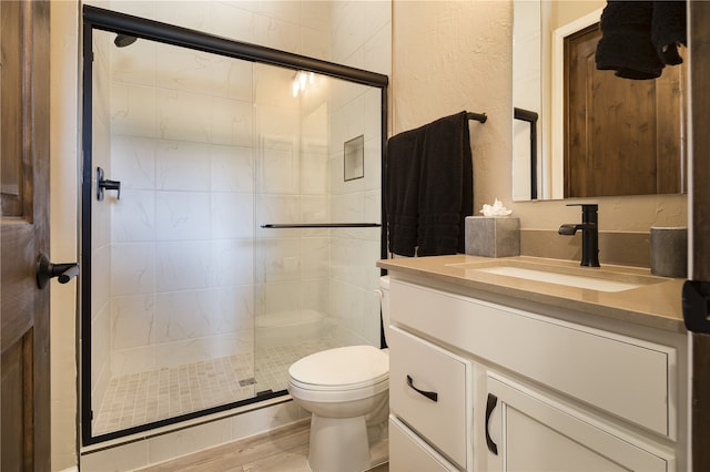 bathroom with vanity, a shower with door, toilet, and hardwood / wood-style floors