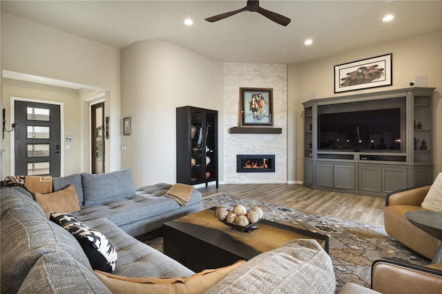 living room featuring a fireplace, ceiling fan, and wood-type flooring