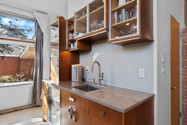 kitchen with sink, light tile patterned floors, light stone counters, decorative backsplash, and beverage cooler