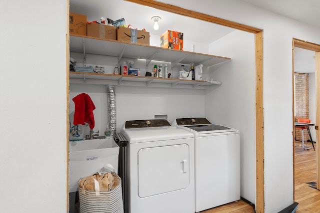 washroom with washing machine and dryer, sink, and light wood-type flooring