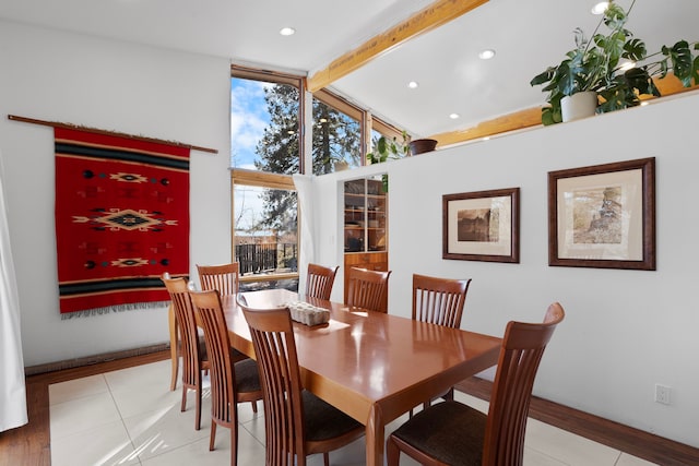 dining room with light tile patterned floors, beam ceiling, and high vaulted ceiling