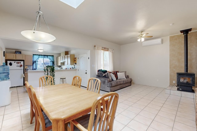 tiled dining room with ceiling fan, a wealth of natural light, a wall mounted AC, and a wood stove