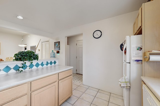 kitchen with light tile patterned floors, light brown cabinets, hanging light fixtures, and white appliances