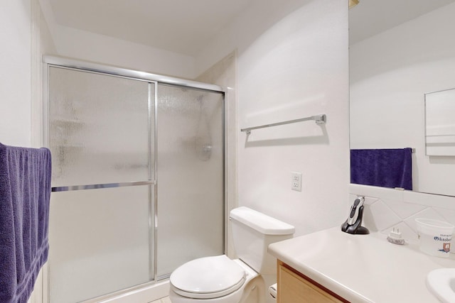 bathroom featuring a shower with shower door, vanity, toilet, and tasteful backsplash