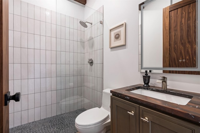 bathroom featuring toilet, vanity, and a tile shower