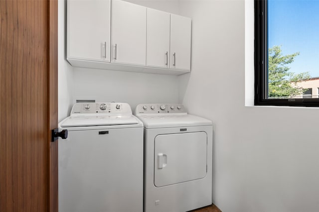 clothes washing area featuring washer and clothes dryer and cabinets