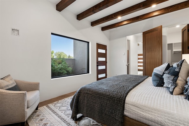 bedroom with a walk in closet and beam ceiling