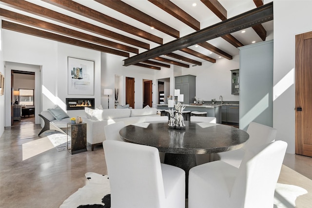 dining space with beam ceiling, sink, and concrete floors