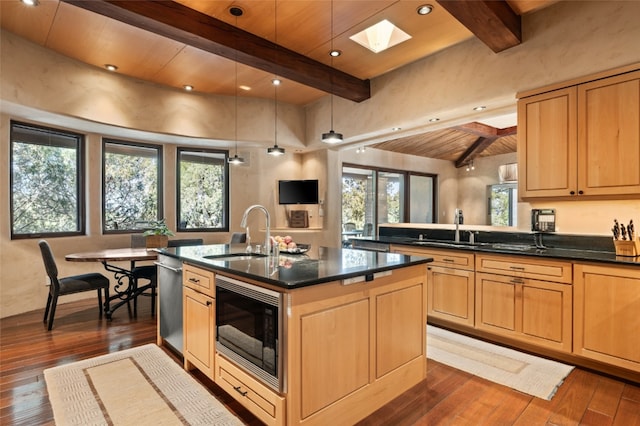 kitchen with a center island with sink, a skylight, built in microwave, and sink