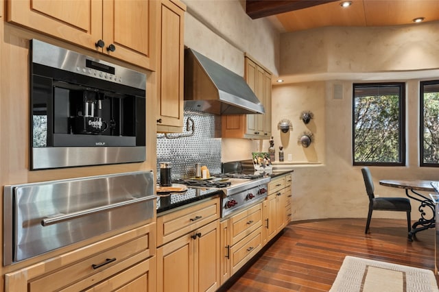 kitchen featuring dark hardwood / wood-style floors, stainless steel gas stovetop, beamed ceiling, light brown cabinetry, and wall chimney exhaust hood