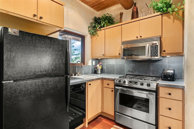 kitchen with stainless steel appliances, light brown cabinetry, sink, backsplash, and tile countertops