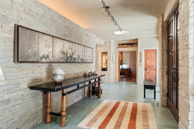 corridor featuring rail lighting and tile patterned flooring