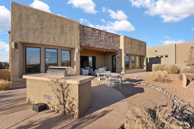 back of property with exterior kitchen and a patio area