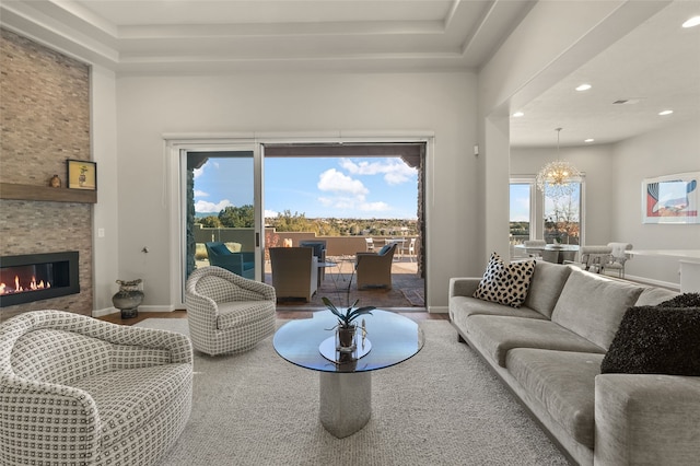 living room featuring a stone fireplace and a notable chandelier