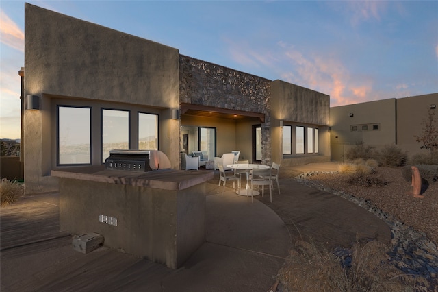 back house at dusk featuring a patio area