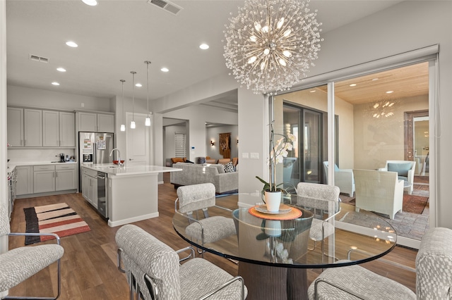 dining room with dark wood-type flooring, sink, and a chandelier