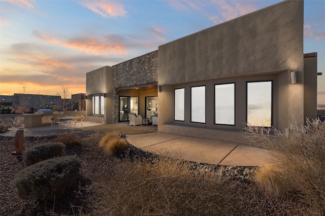 back house at dusk featuring a patio