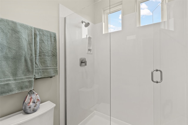 bathroom with a shower with shower door and toilet